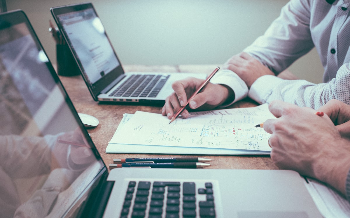 Zwei Männer sitzen vor ihren Laptops und erarbeiten einen Finanzplan