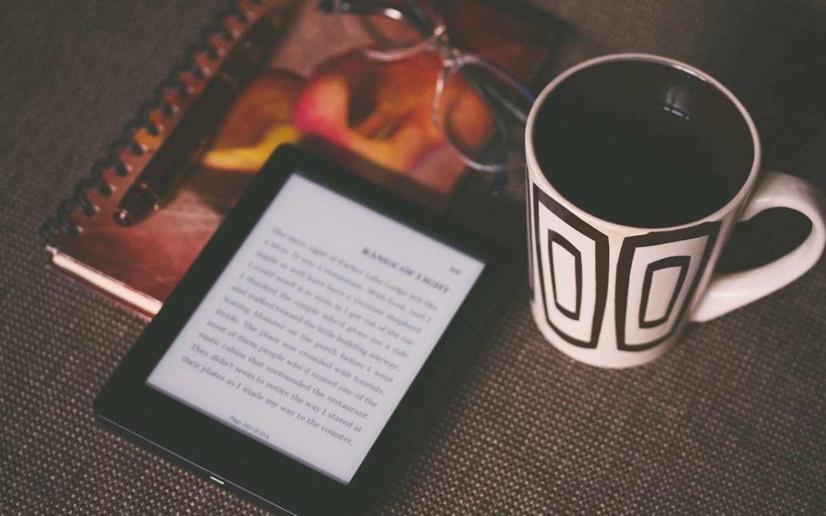 Kindle neben Kaffeetasse und Notizbuch