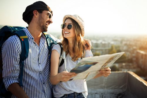 Ein glückliches Pärchen lächelt sich an, während sie eine Citymap in der Hand halten.